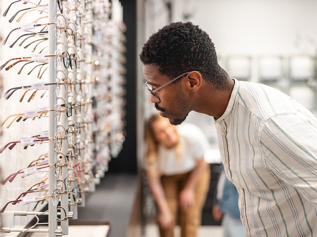 Framåtlutad man ser igenom glasögonutbud i butik